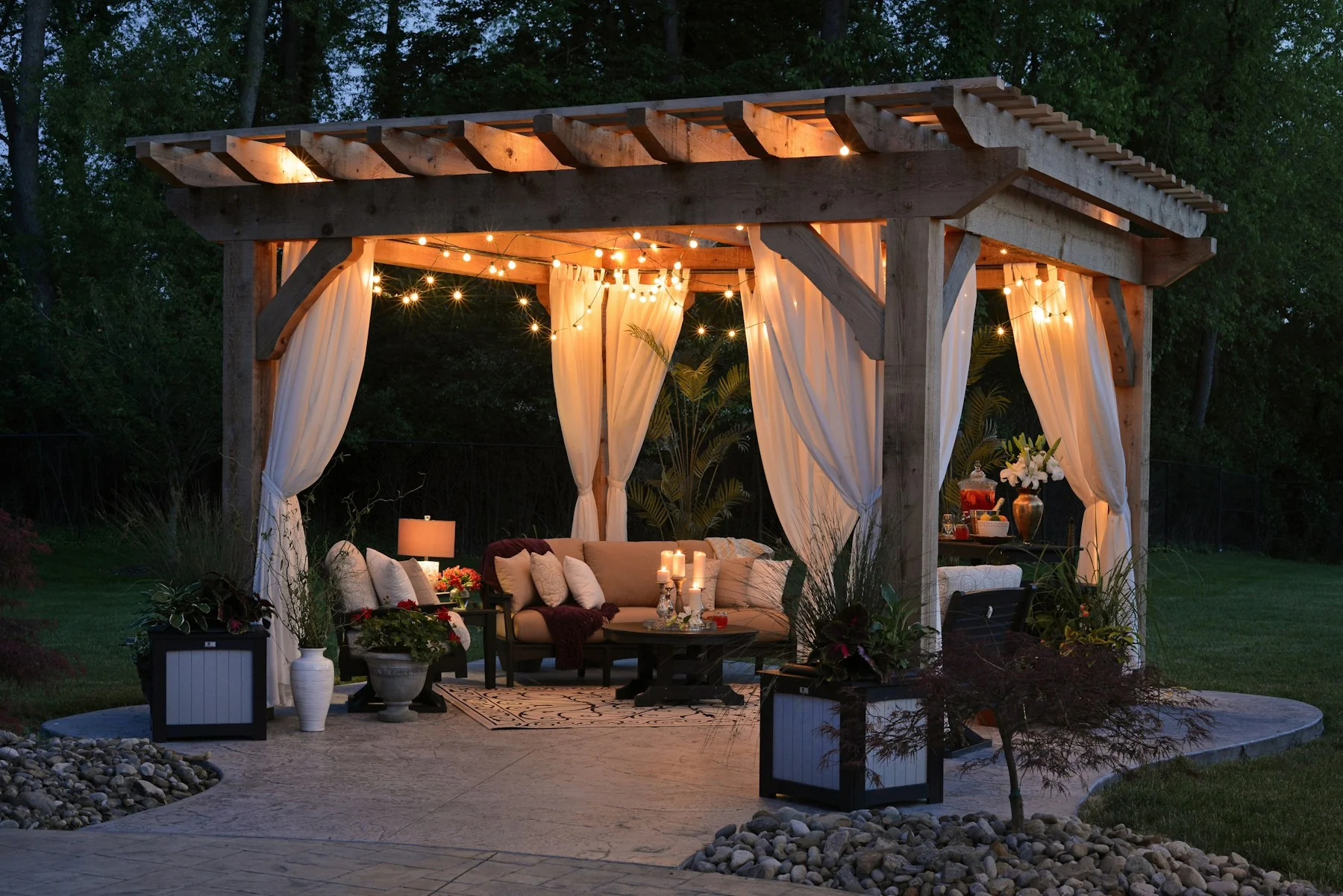 Warm timber pergola with curtains and evening lighting