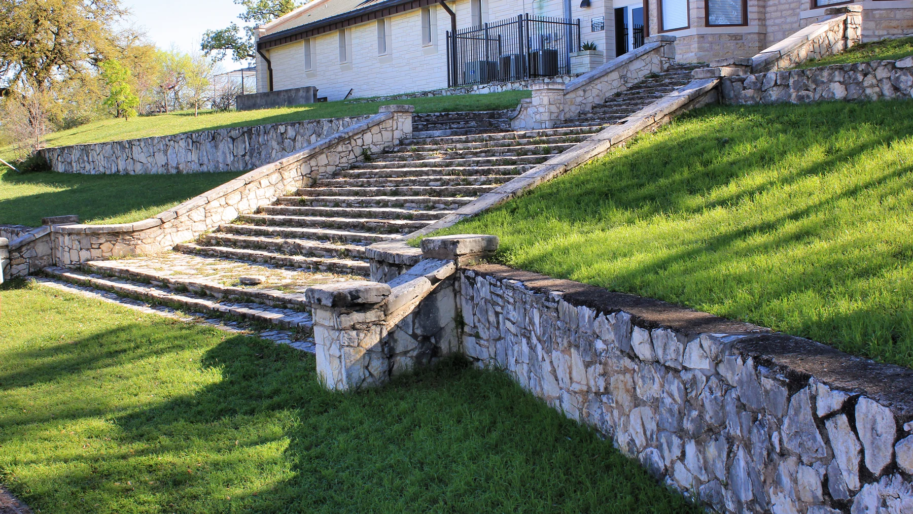 Stone walls and broad stairway creating terraces on a steep grassy site