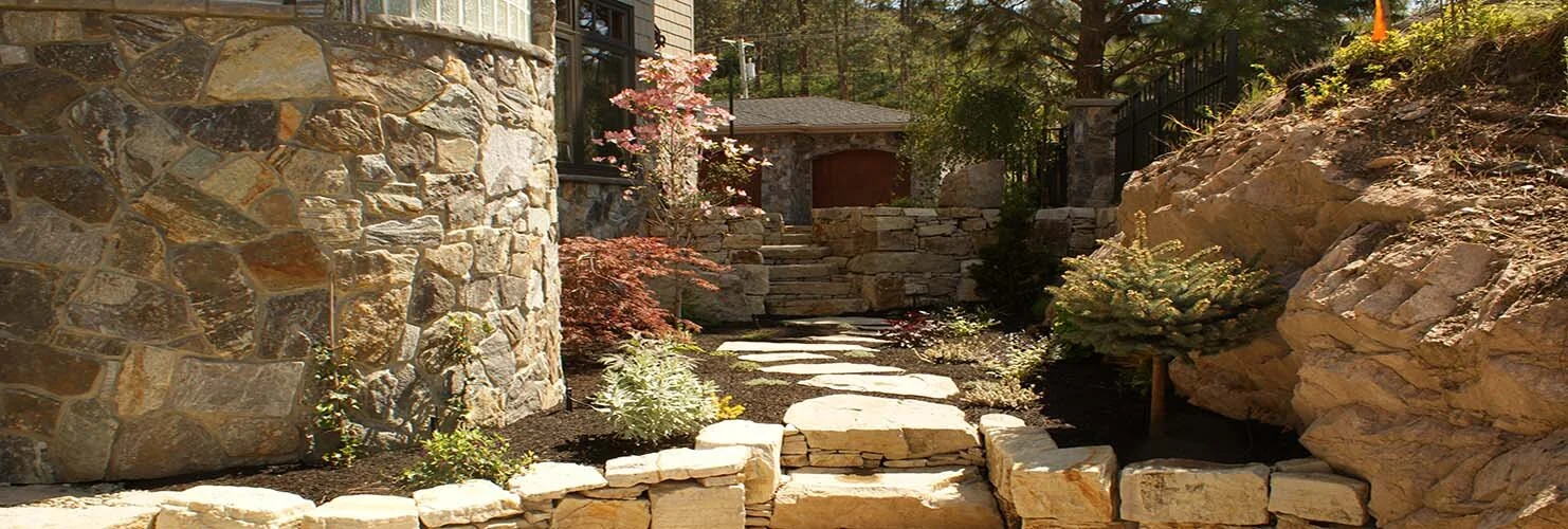 Natural rock retaining walls and stepped path integrated into planted landscape